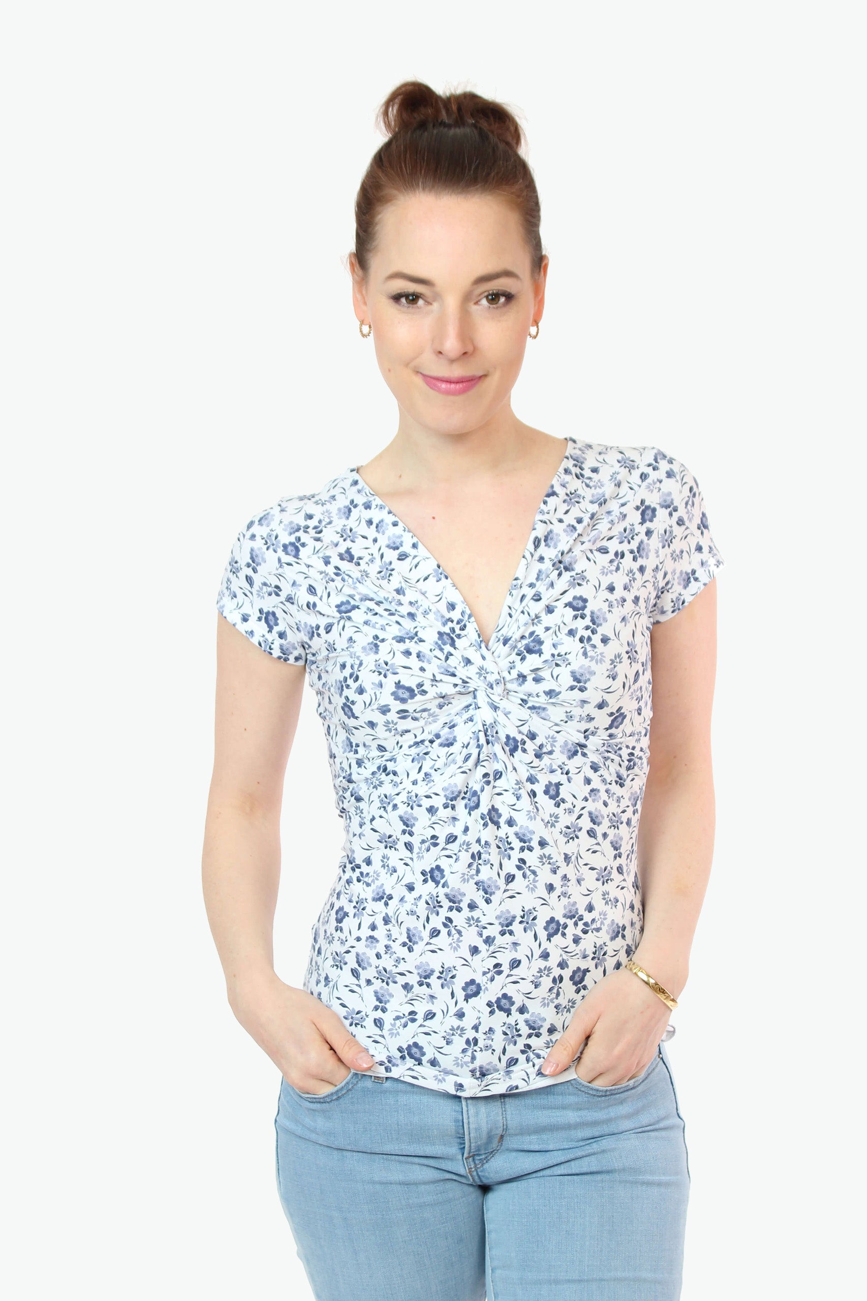 Frau in einem weißen Knotenshirt mit blauen Blumen und kurzen Ärmeln  von LA.LUKA Berlin.